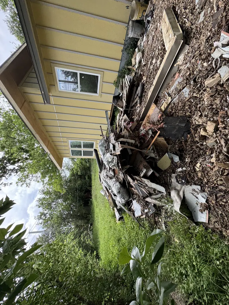 Torn out siding and debris piled along the side of a house in Austin before haul off