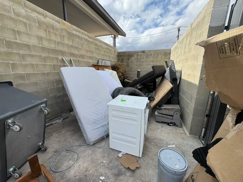 Trash enclosure in Kyle packed with a mattress, dryer, recliner and boxes