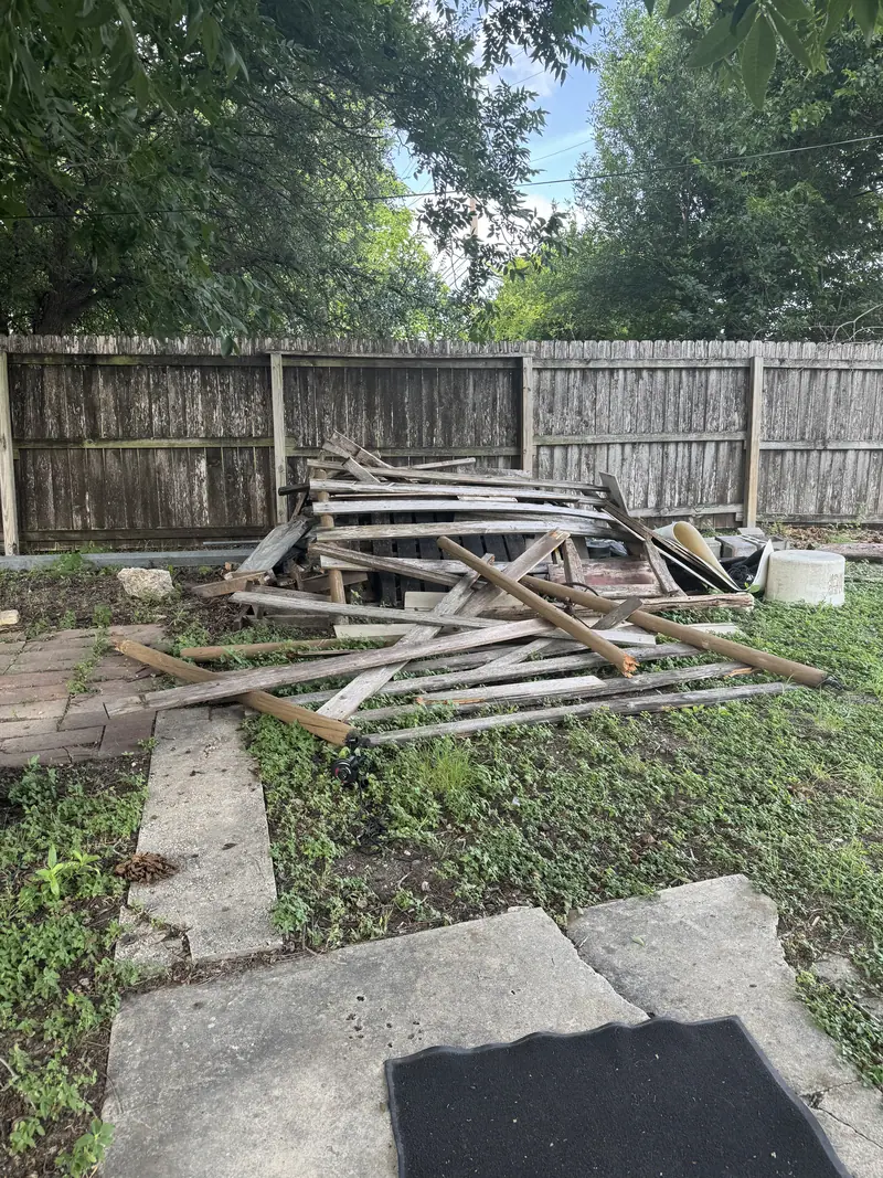Torn out boards and old lumber piled along a backyard fence line in San Marcos before haul off