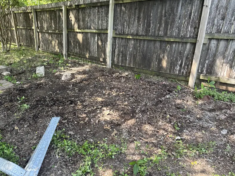 The same San Marcos backyard fence line after the lumber pile was cleared and hauled